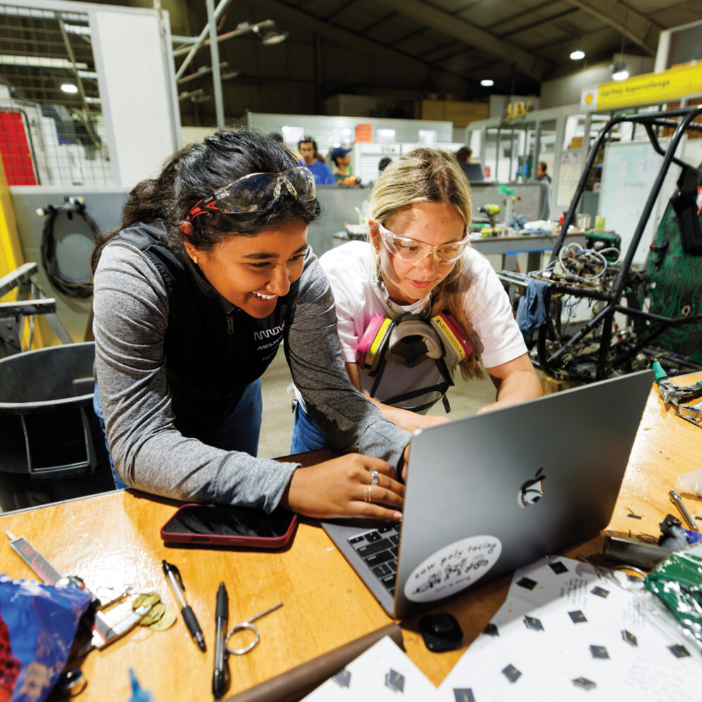 Two Cal Poly Racing students work at a laptop inside the Aero Hanager
