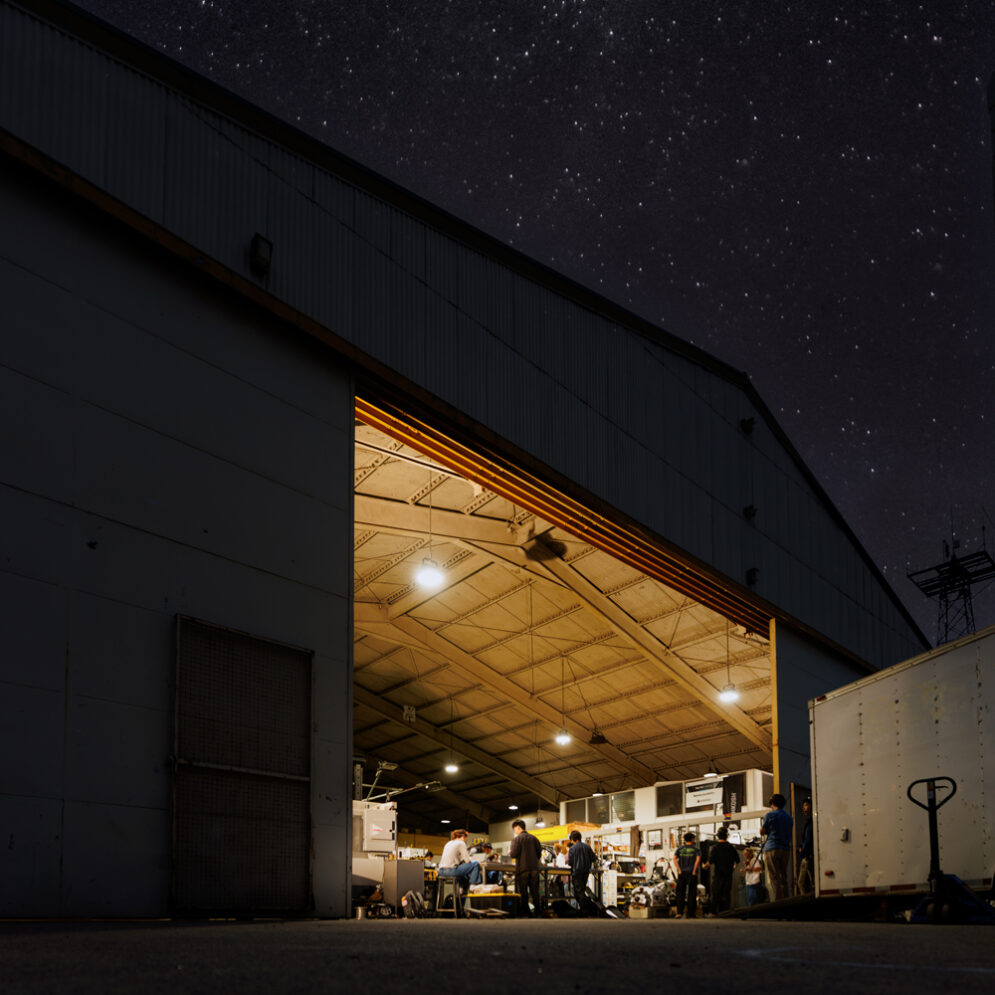 The exterior of the Aero Hangar at night while students work on Cal Poly Racing vehicles inside