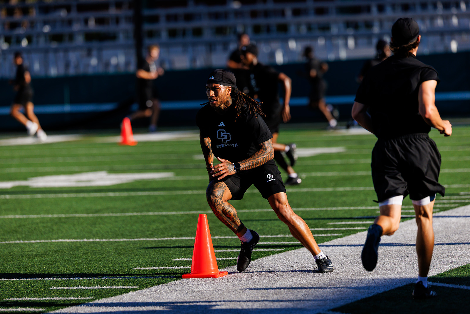 Football players running sprints down the field marked with cones.