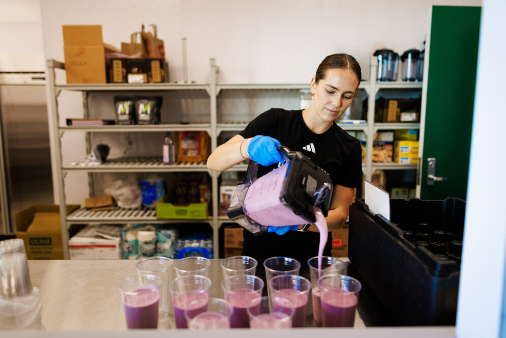 A nutrition student is pouring smoothies from a blender at the Madden Center.