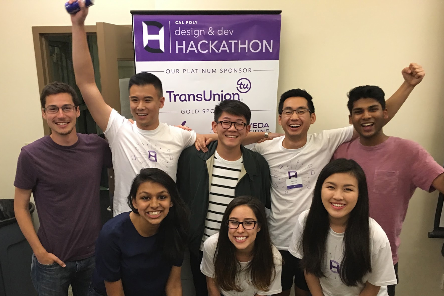 Eight people pose in front of a Cal Poly desing and dev hackathon banner