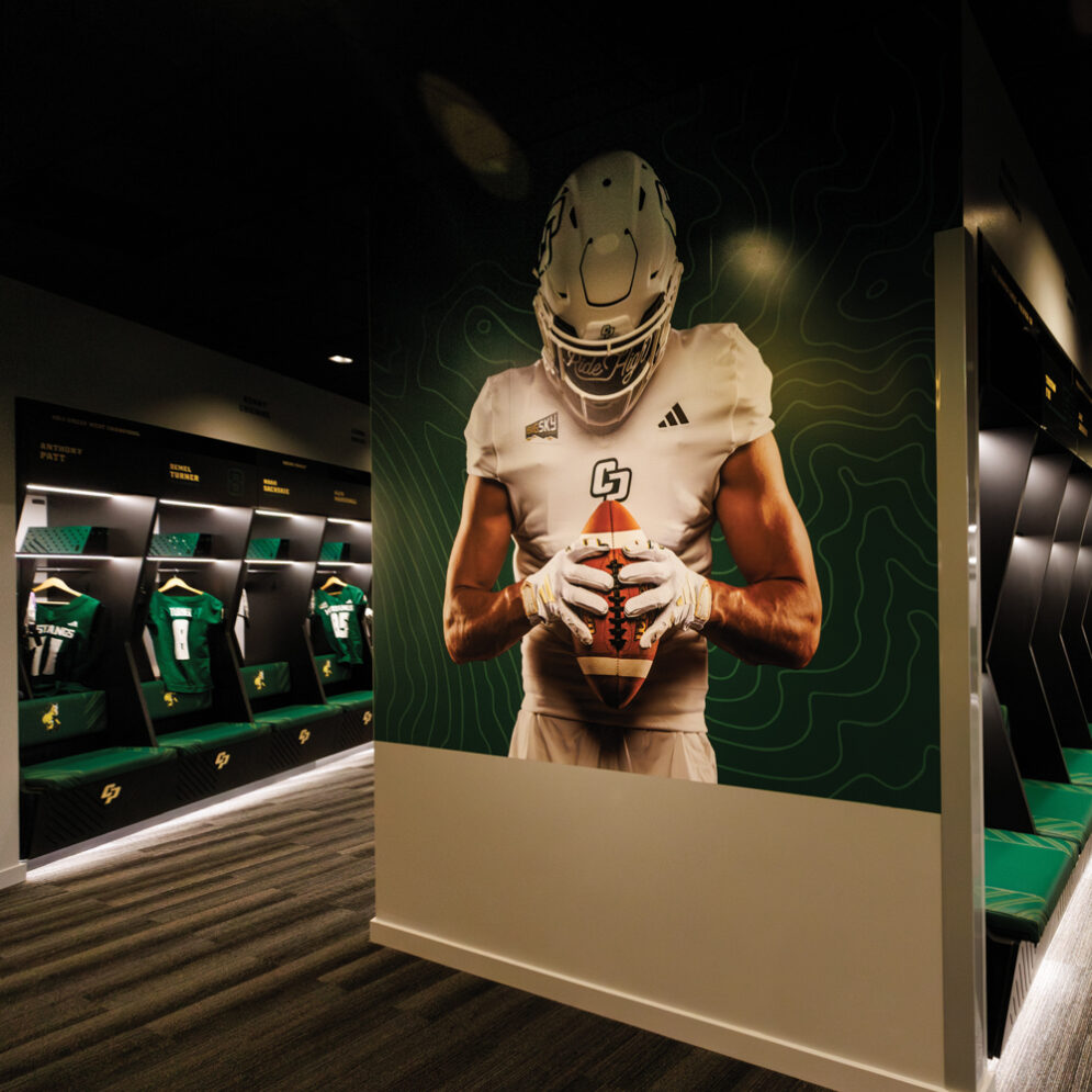 The Cal Poly Football team's locker room with a photo of a player in uniform on the wall