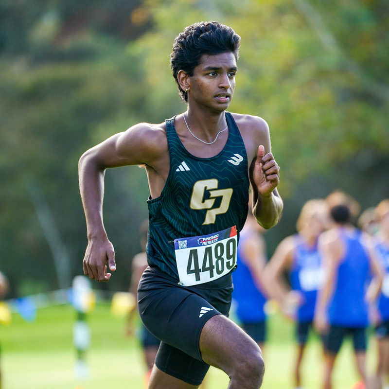A Cal Poly men's cross country team athlete runs during a meet while wearing a uniform and number