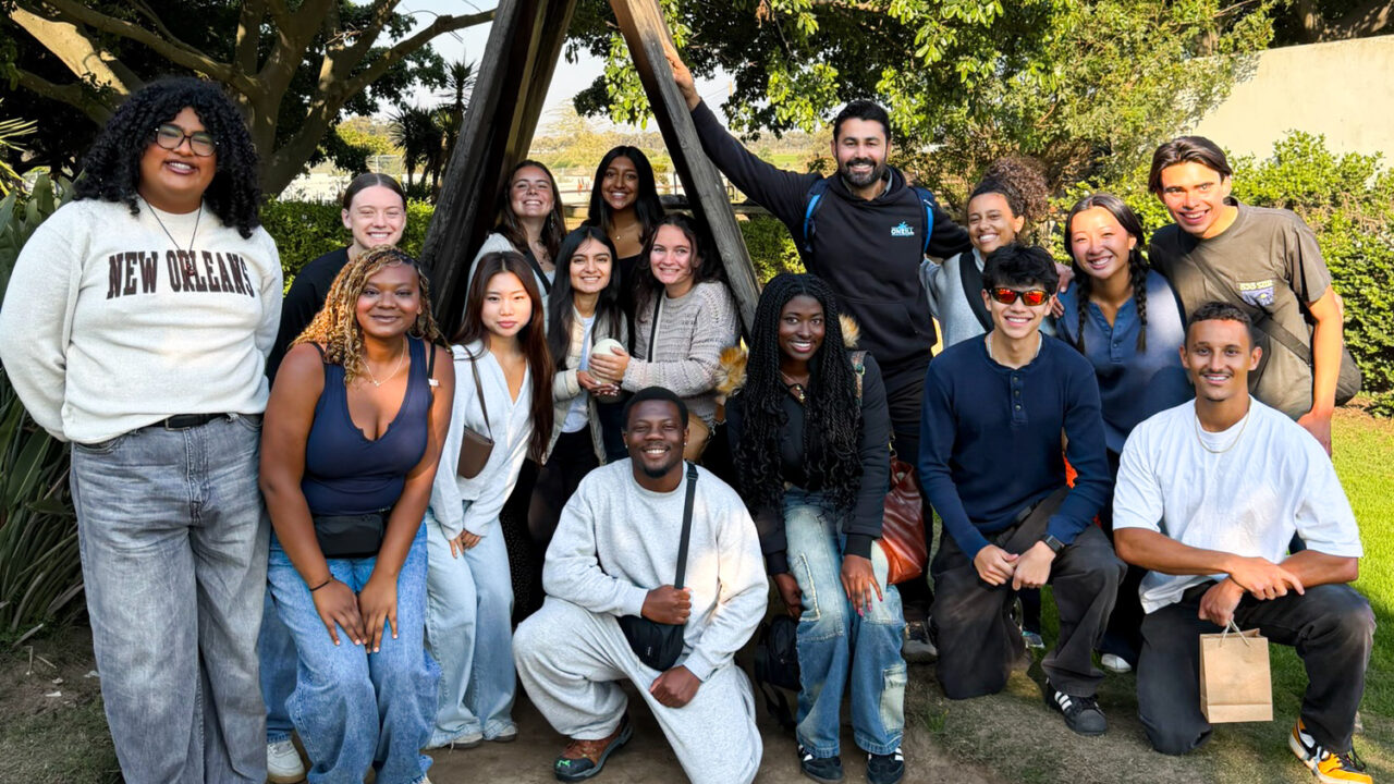 A group of students poses near greenery