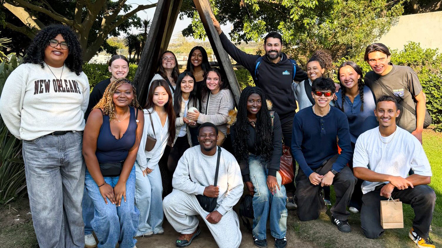 A group of students poses near greenery